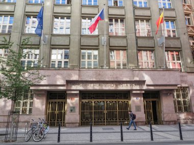 Prag, Çek Cumhuriyeti - 10 Mayıs 2024: Prag 'daki bir hükümet binası, girişinde Çek ulusal bayrağı da dahil olmak üzere birden fazla bayrak sergiliyor. Bisikletler ön tarafa park edilmiş, bu da bisiklete uygun bir yer olduğunu gösteriyor..