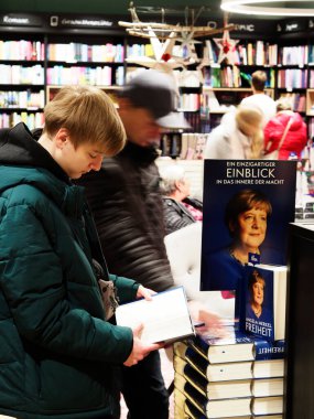 Almanya, Passau - 5 Aralık 2024: Genç bir adam Bayan Merkel 'in kitabını bir kitapçıda okuyor. Eski Alman şansölyenin 