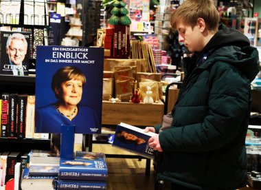 Almanya, Passau - 5 Aralık 2024: Genç bir adam Bayan Merkel 'in kitabını bir kitapçıda okuyor. Eski Alman şansölyenin 
