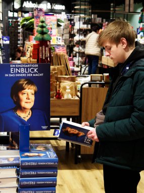 Almanya, Passau - 5 Aralık 2024: Genç bir adam Bayan Merkel 'in kitabını bir kitapçıda okuyor. Eski Alman şansölyenin 