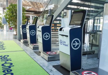 Horsching, Avusturya - 12 Ağustos 2025: Linz Havaalanı terminalinde bir sıra otomatik kontrol gişesi. Büfeler modern tasarım ve yerde 