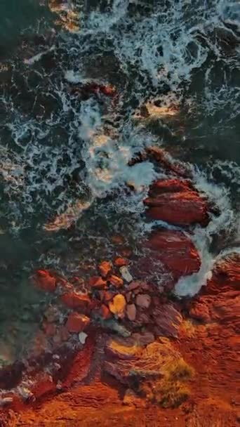 日没時の海の中の赤い岩や波の空中トップビュー 垂直ビデオ — ストック動画