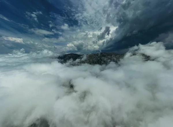 Aerial view of mountains in dramatic storm clouds. Beautiful landscape with mountain peak in fog