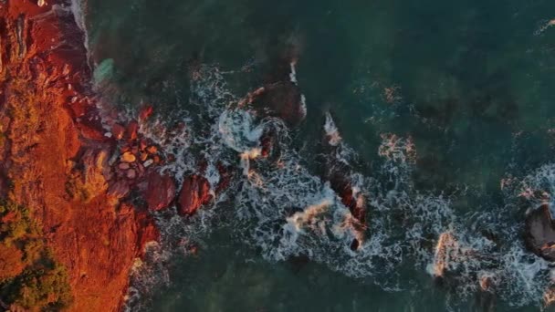 スローモーション 4Kで海の中の赤い岩や波の空中トップビュー — ストック動画