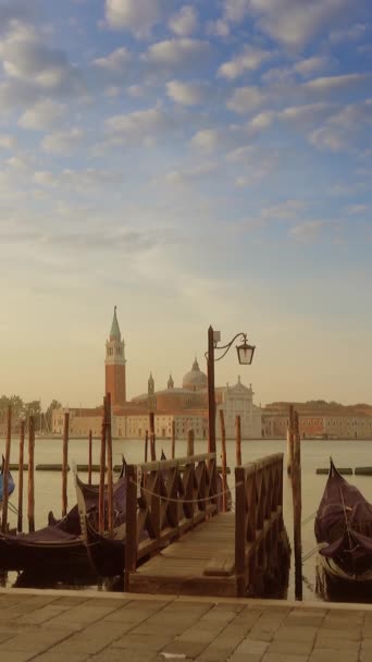 朝の背景にサン ジョルジョ マッジョーレ教会と運河グランデ上の伝統的なゴンドラ マルコ ヴェネツィア イタリア 垂直ビデオ — ストック動画