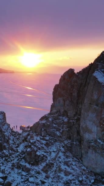 ロシアのシベリアの冬の凍った湖バイカル湖の神聖な場所である日没でのシャーマン岩の空中観察 バーティカルビデオ — ストック動画