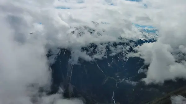 Flying between clouds. Aerial view of snowcapped mountains in clouds, Austrian Alps, Austria