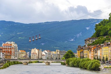 Fransa 'nın Grenoble, Auvergne-Rhone-Alpes bölgesindeki Isere Nehri. Arka planda Pont Marius-Gontard Köprüsü, Grenoble-Bastille Kablo Aracı (Telepherique) ve Alp Dağları