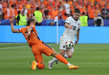 Berlin, Almanya - 25 Haziran 2024: Hollanda 'dan Xavi Simons (L), Almanya' nın başkenti Berlin 'deki Olympiastadion' da oynanan UEFA 2024 grup etap maçı sırasında Avusturyalı Romano Schmid ile top için mücadele ediyor.