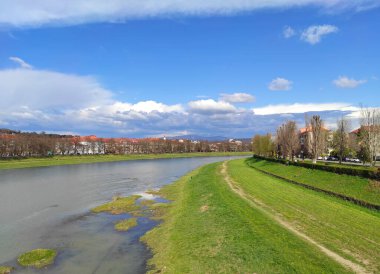 Uzhhorod şehri ve Uzh nehri, Transcarpathia, Ukrayna manzaralı bahar manzarası. Bereketli bir nehir manzarası. Parlak mavi bir gökyüzü altında, baharın başında dağınık bulutlar.