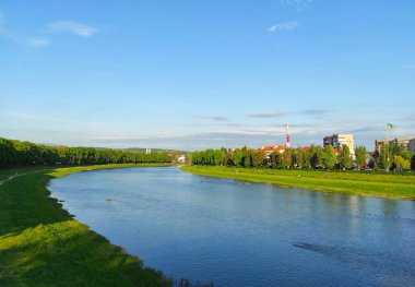 Uzhhorod şehri ve Uzh nehri, Transcarpathia, Ukrayna manzaralı. Huzurlu bir nehir, her iki taraftaki ağaçlarla çevrili yemyeşil çayırlarda kıvrılır.