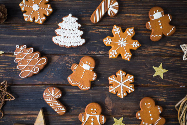 Christmas cookies of various shapes with sugar decor glaze on the wooden table, flat lay with decor
