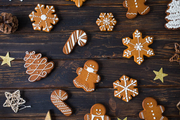 Christmas cookies of various shapes with sugar decor glaze on the wooden table, flat lay with decor