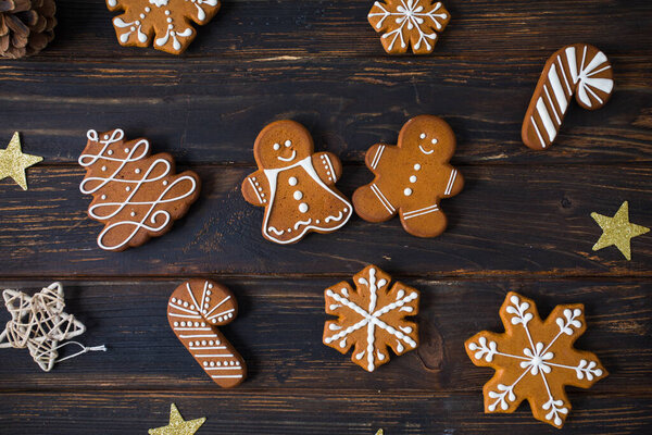 Christmas cookies of various shapes with sugar decor glaze on the wooden table, flat lay with decor