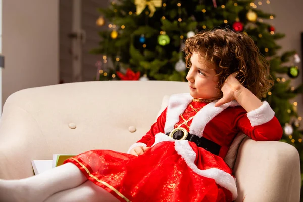 穿着圣诞礼服的可敬的女孩靠近装饰着彩灯的经典圣诞树 — 图库照片