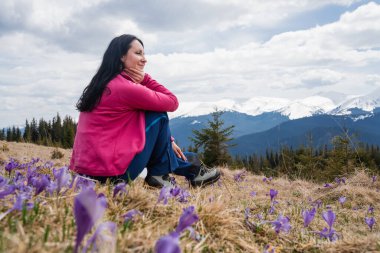 Yürüyüş yapan kadın, bahar başında Carpathian dağlarında safran çiçeklerini sever.