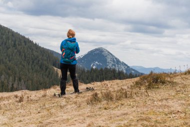Sırt çantalı bir kadın dağın tepesinde dikilirken manzaranın tadını çıkarıyor..