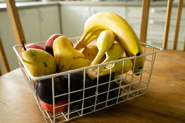 有新鲜水果的篮子放在厨房的桌子上 香蕉放在前边 图库照片