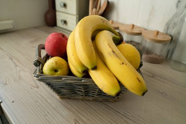 Mutfakta taze meyve dolu sepet, ön planda muzlar.