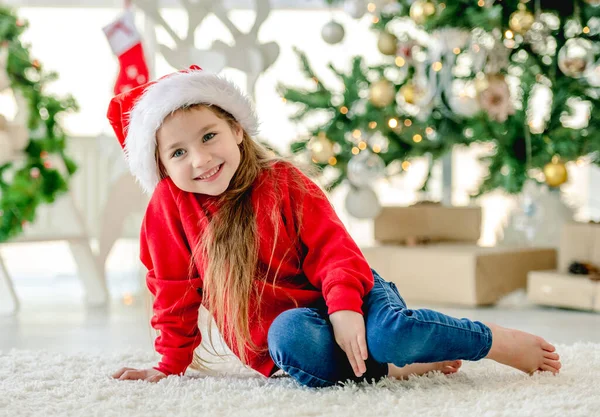 크리스마스 시간에 모자를 소녀가 크리스마스 트리로 장식된 바닥에 크리스마스 시간에 — 스톡 사진