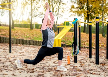 Sporcu kız sonbaharda yoga yaparken poz veriyor. Park alanında egzersiz yapan genç bir kadın.