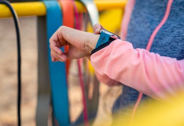 Sonbahar zamanı dışarıda spor yaparken akıllı fitness gözlemi yapan bir kız. Spor teknolojisi aleti olan genç bir kadın.