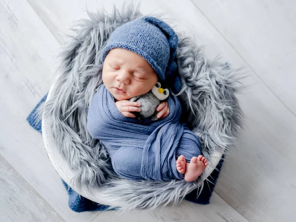 新生児の少年は 鳥のおもちゃを保持し 流域スタジオの肖像画で寝て生地に飲み込まれました 乳児期の子供の昼寝 — ストック写真