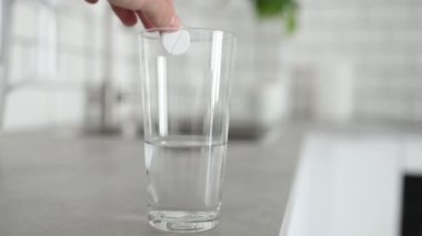 Köpüklü su bardağında eriyen tüylü haplar. Şeffaf sıvıda aspirin vitamin ilacı