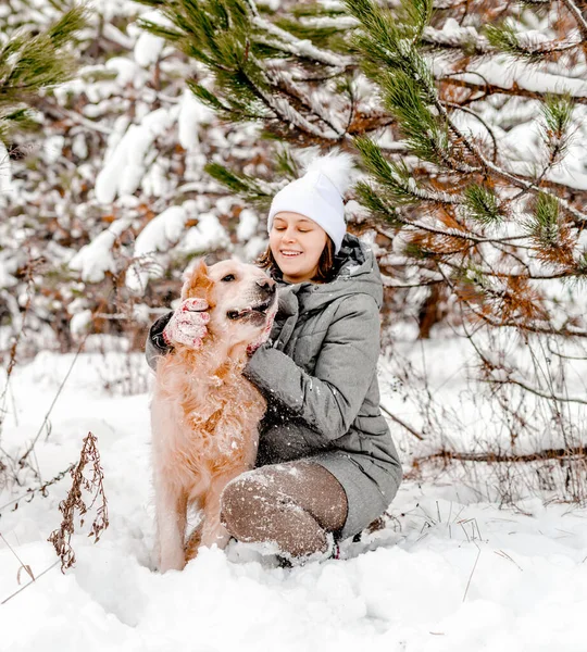 小女孩在雪地森林里用树爱抚金毛猎犬 在寒冷天气下带着小狗带着雪花外出的年轻女人 — 图库照片