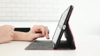 Çocuk kız eli tablet ekranına dokunuyor ve ekrandaki bilgileri yakınlaştırıyor. Evinde modern cihazlı bir kadın çocuk var.