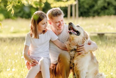 Dad and his daugter play with golden retriver dog
