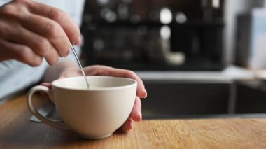 Girl hand stiring coffee cappuccino in cup at kitchen for breakfast. Morning espressoo latte beverage at home