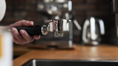 Girl hand holding portafilter and making fresh aromatic coffee cappuccino using modern coffee maker at home. Aroma espresso preparation process