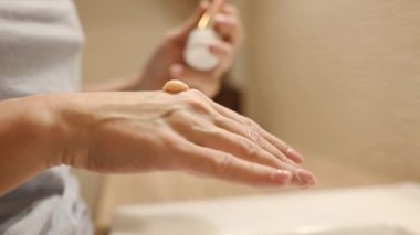 Beautiful girl applying hand cream during daily spa beauty routine. Skin care procedure with lotion and massage