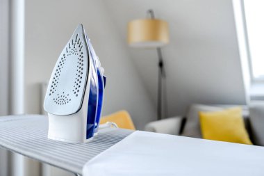 Ütü masasındaki kırışık giysiler için elektrikli ütü. Ev idaresi için modern ev aletleri aracı