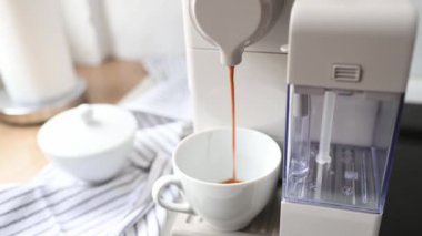Kahve makinesi beyaz fincanda kapuçino hazırlıyor. Kahvaltıda sıcak kafein içeceği ve fincanda kahve.