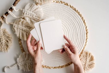 Girl hands holding watercolor paper postcard blanks on scandinavian decor background. Artist with aquarelle empty cards in minimal natural design with copy space