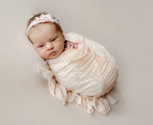花の花輪を身に着けている新生児の女の子は眠りに落ちる 幼児子供嘘Swaddledで桃生地スタジオポートレート — ストック写真