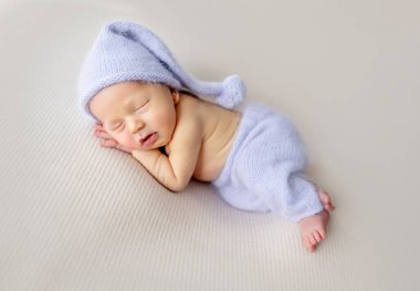 Newborn baby boy with bunny toy sleeping wearing knitted pants and hat. Little infant child napping