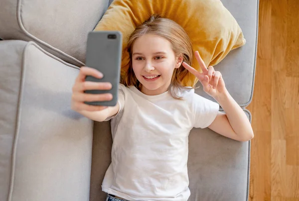 Chica Preadolescente Con Teléfono Inteligente Haciendo Selfie Tumbado Sofá Casa —  Fotos de Stock