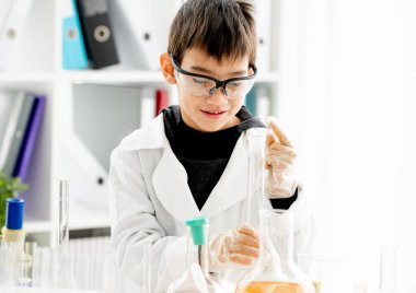 İlköğretim fen dersinde koruma gözlüğü takan öğrenci kimya deneyi yapıyor. Laboratuvarda ekipman tüplü gözbebeği.