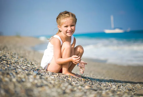 在她的手在海滩上的小石子的女孩 — 图库照片