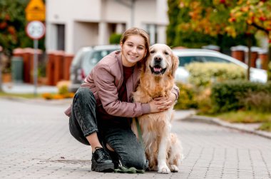 Golden Retriever köpek dantelini açık havada giyen reşit olmayan bir kız. Safkan evcil köpeği olan güzel bir çocuk sokakta yürüyor.