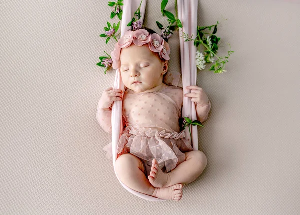 花で飾られたスイングでドレスと花輪睡眠を身に着けている新生児の女の子 可愛い赤ちゃんの子供スタイリッシュなスタジオポートレート — ストック写真