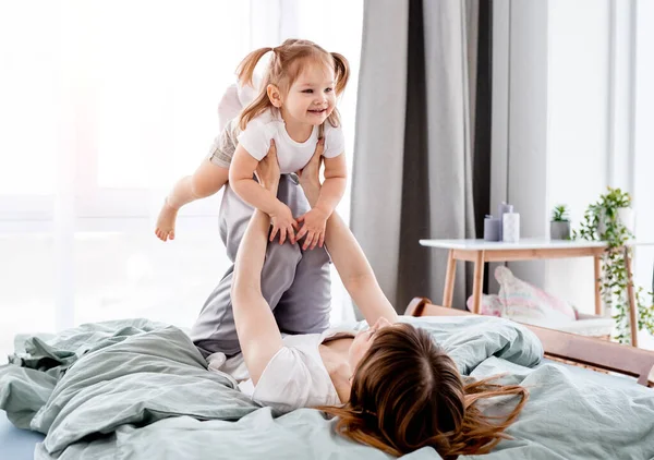 Young Mother Playing Daughter Bed Holding Child Her Legs Mom — Stock Photo, Image