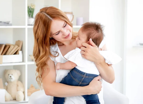 自宅でかわいい赤ちゃんを抱きしめる若い母親 — ストック写真