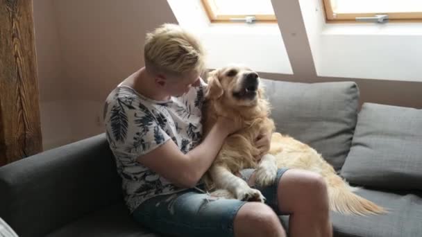 Przystojniak Pieszczący Psa Golden Retrievera Przytulający Zwierzaka Siedzącego Kanapie Domu — Wideo stockowe