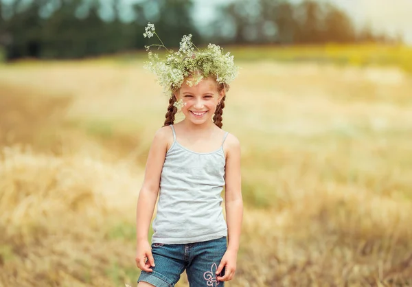 フィールド上の彼女の頭に花輪を捧げるとの幸せな女の子 — ストック写真