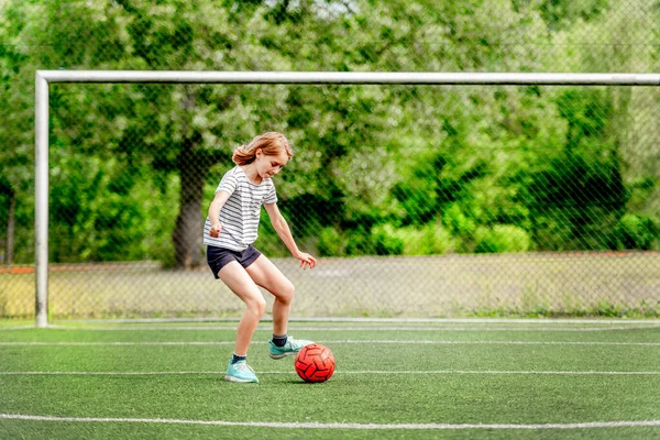 試合中は芝生の上でサッカーボールをしている可愛い女の子 かわいいです女性子供でサッカー場ゲームをプレイ — ストック写真