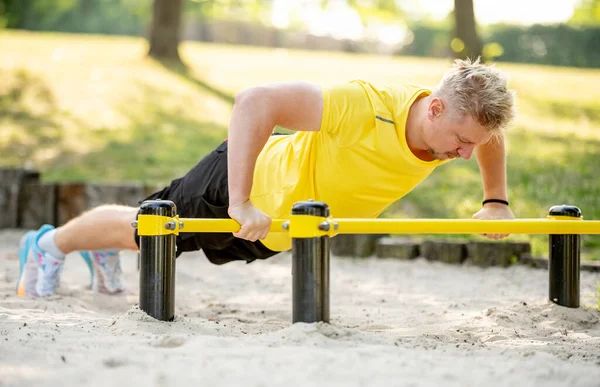 男子做俯卧撑与水平酒吧户外公园为健康的福祉 运动员正在做强身健体运动 — 图库照片